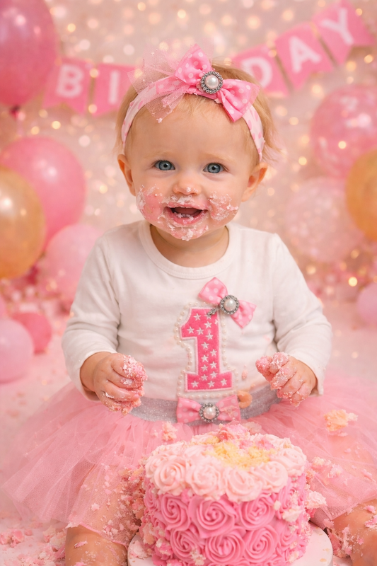 Baby girl in 1st Birthday Tutu Set: long-sleeve romper, 3-D pearl- and flower-embellished 1, pink tulle tutu.
